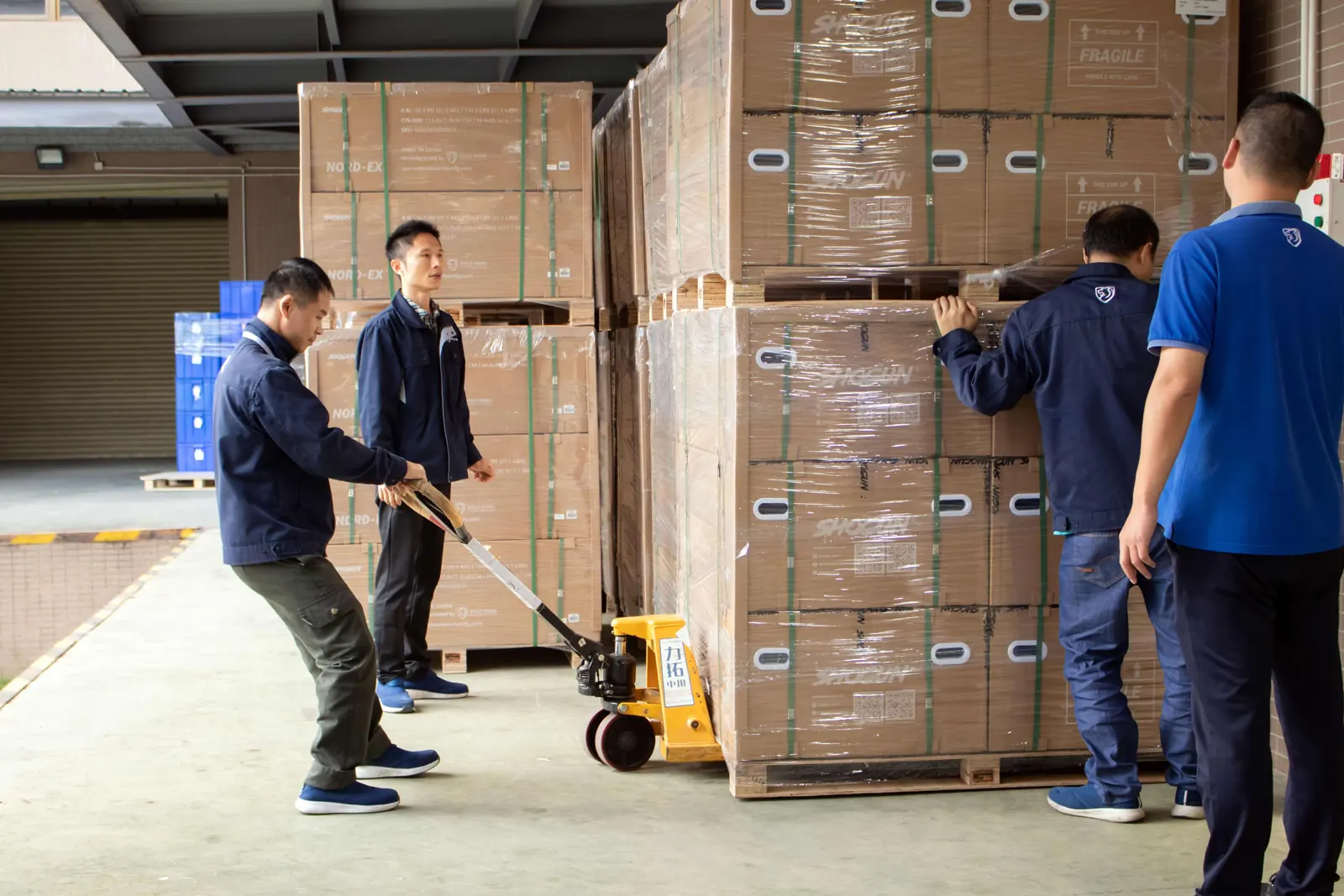 Warehouse team staging wrapped pallets for container loading