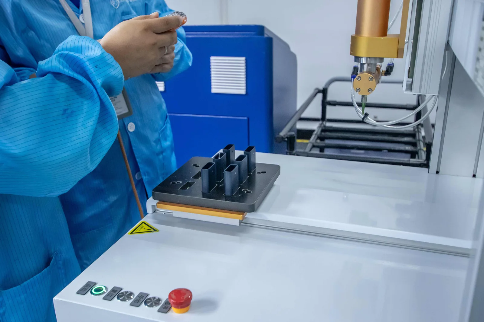 An automated gantry cell working on a fixture of parts, loaded by an operator in an ESD smock