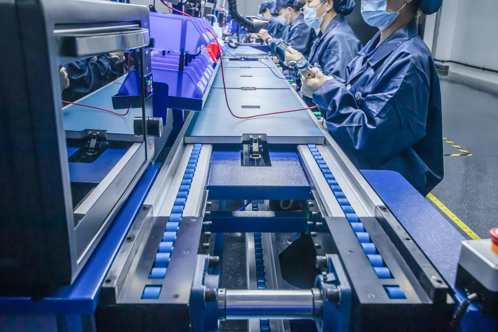 A conveyor running the length of an ESD workbench with operators working alongside it