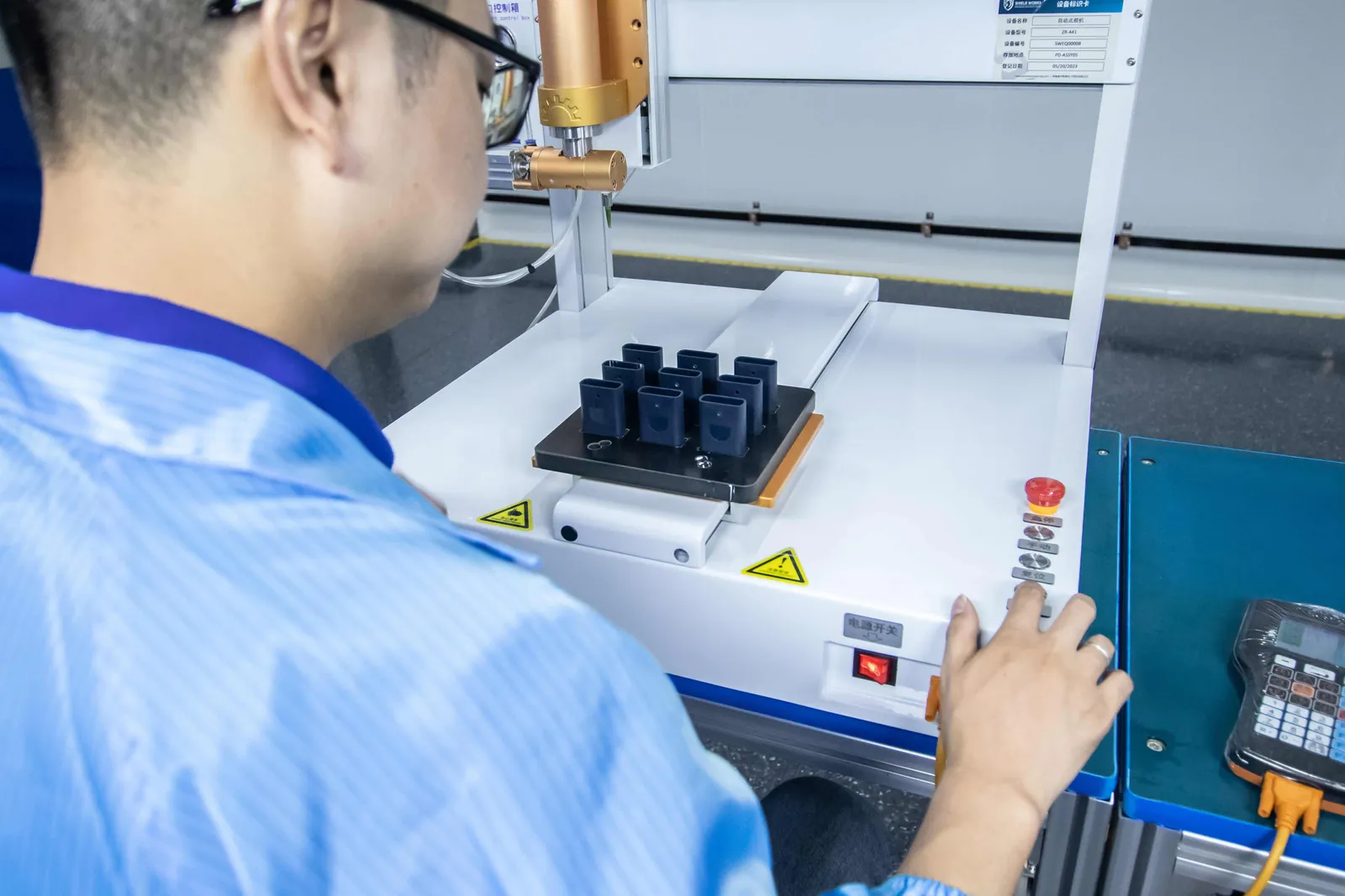 A technician operating an automated test fixture on a batch of parts