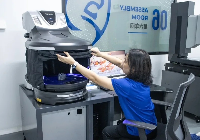 An inspector loading a part into the 3D scanner in Assembly Room 06