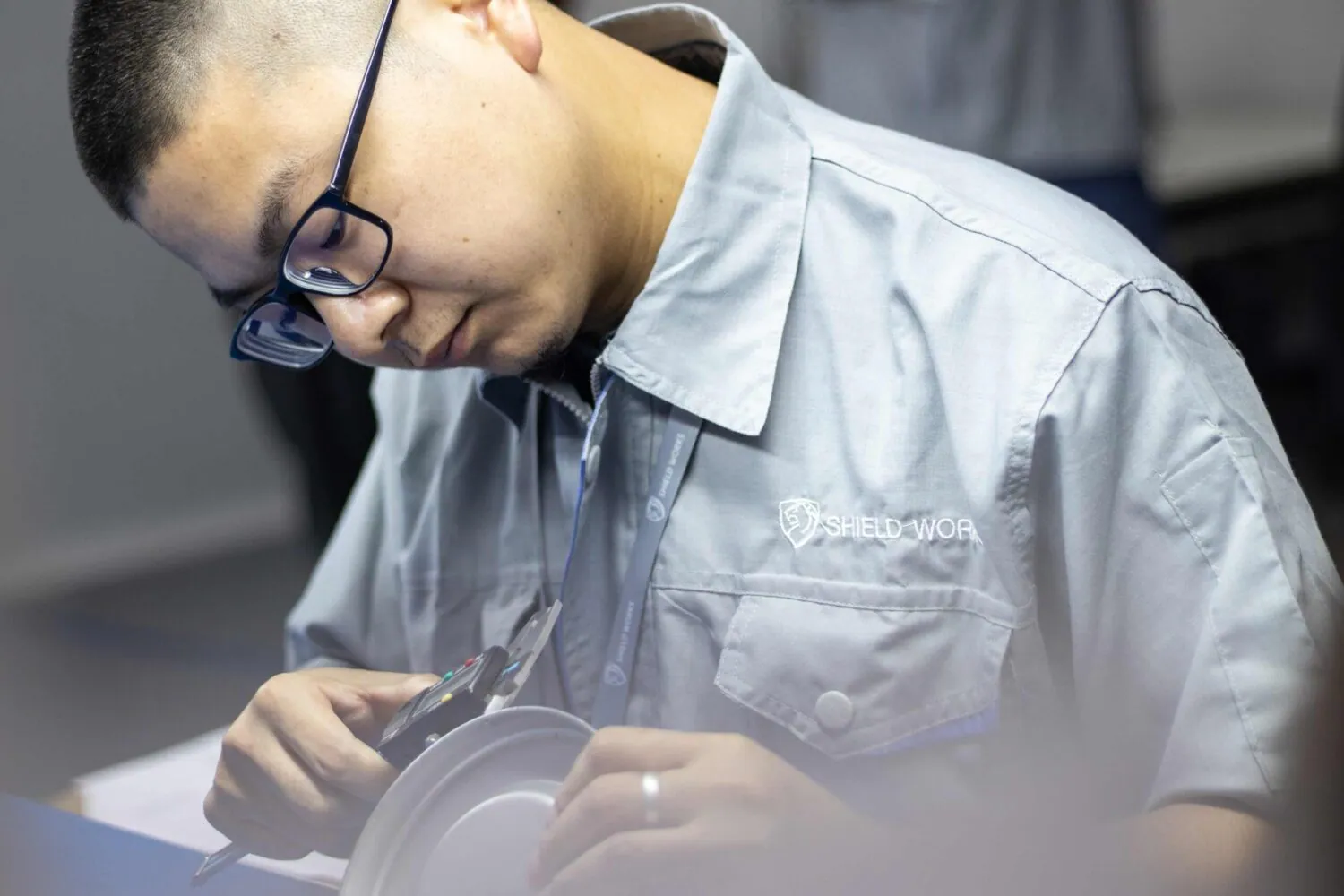 Shield Works engineer in branded uniform inspecting a component with calipers