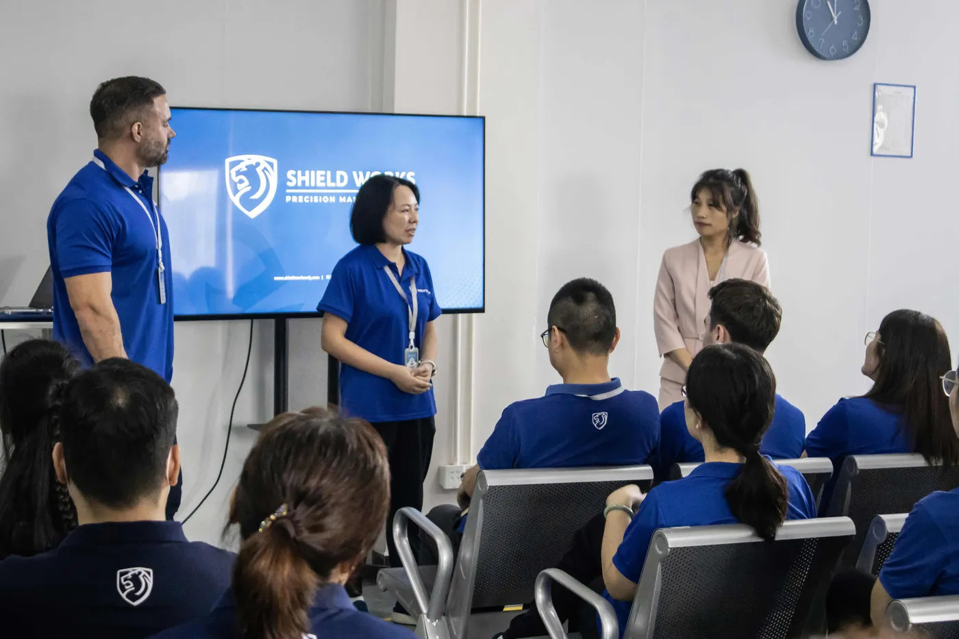Shield Works all-hands meeting with leadership presenting to seated team members