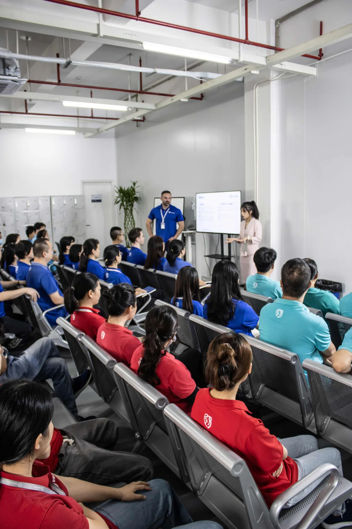 Large all-hands Shield Works team meeting with dozens of staff seated facing leadership at the front of the room