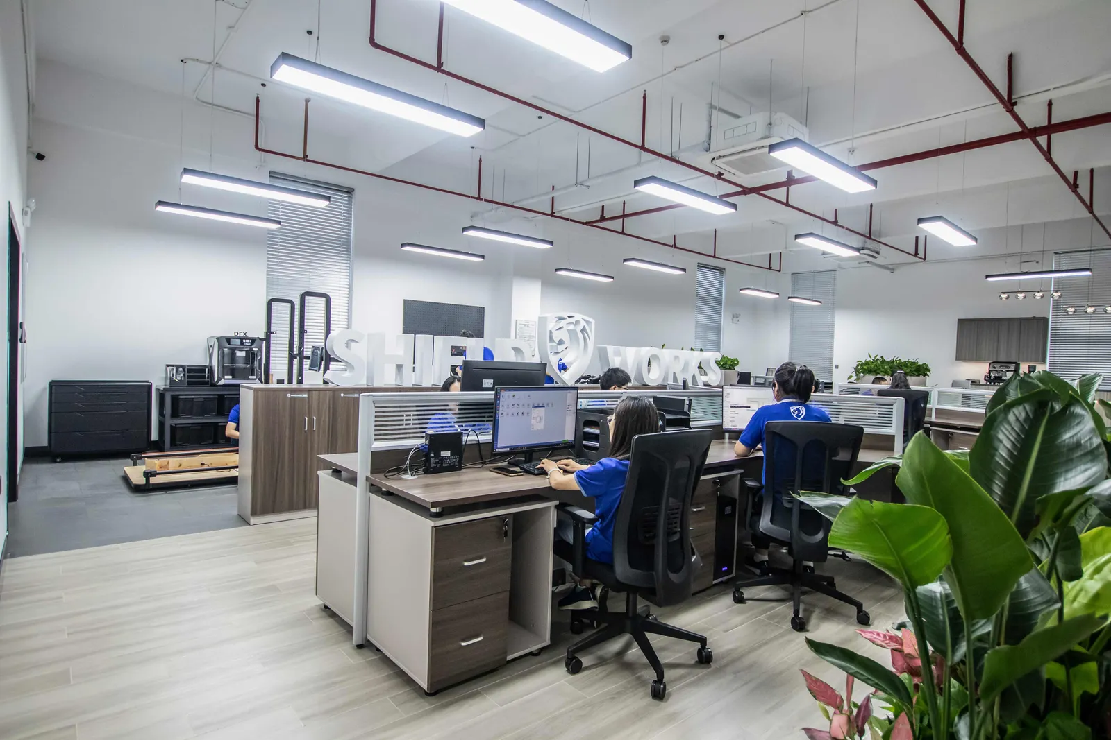 Wide view of the Shield Works engineering office floor with the SHIELD WORKS sign visible